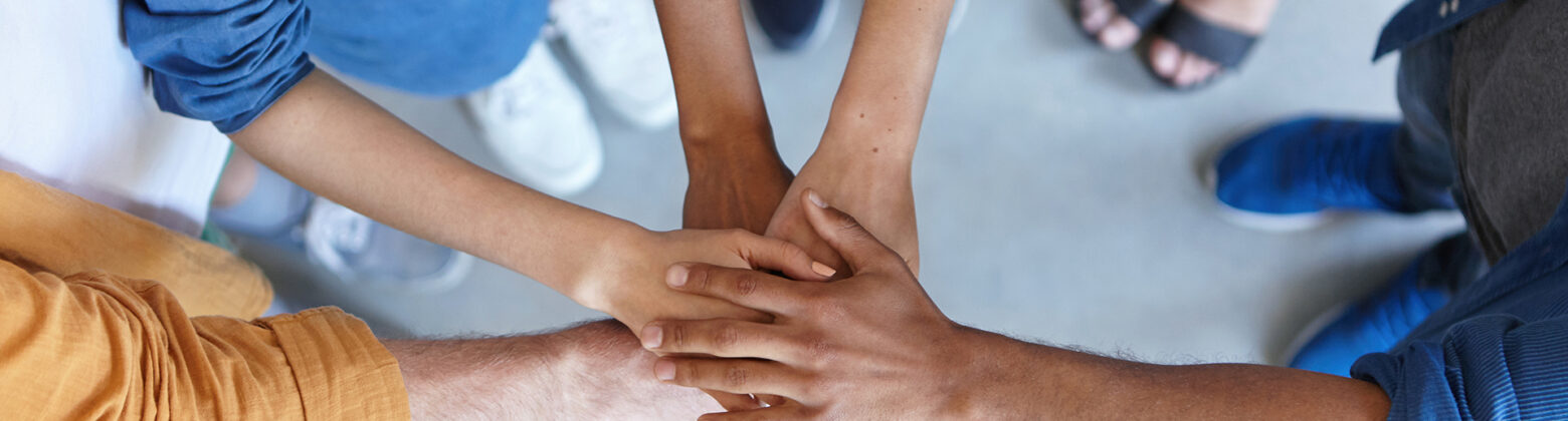 Friendship, partnership, togetherness, collaboration concept. Group of international friends stacking their hands expressing their friendship, agreement and support. People piling their hands